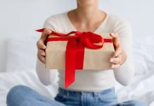 Derfor skal du ikke stole på giveaway-konkurrencer på sociale medier En pige med en gave i hænderne sidder på sengen.