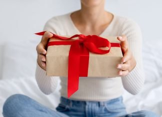 En pige med en gave i hænderne sidder på sengen.