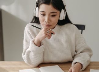 En pige med høretelefoner, der studerer ved sit skrivebord.