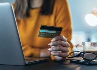 Hvordan fungerer Shein Wallet, og kan den hackes? Pigen foran en bærbare computer med et kreditkort i hånden.