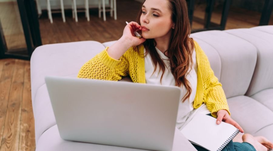 En pige sidder i sofaen foran en bærbare computer