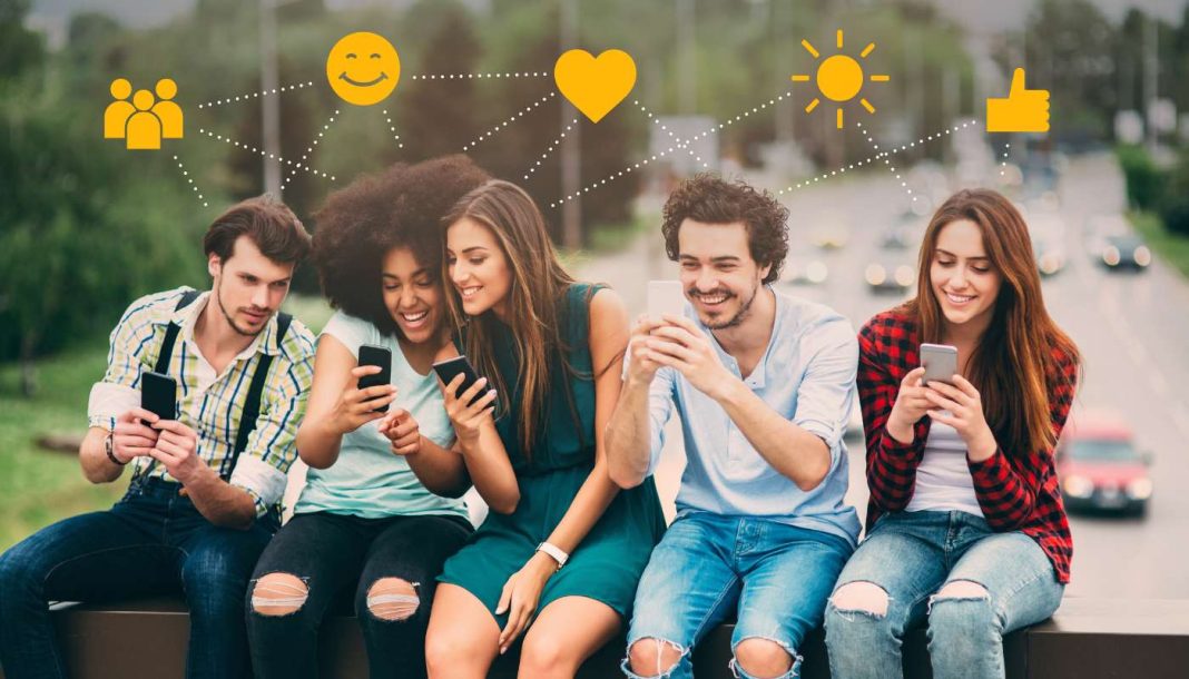 social-media-good Fem unge mennesker sidder på en bænk med smartphones