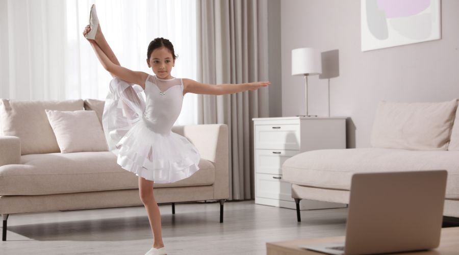 En lille ballerinapige danser foran en bærbar computer