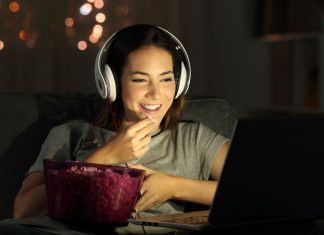 De 8 bedste YouTube-kanaler med explainer-videoer Pige med høretelefoner foran en laptop med popcorn på bordet