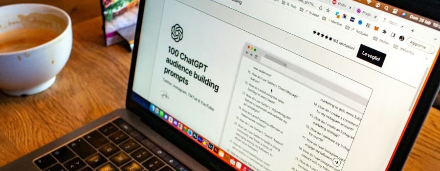 Åben bærbar computer og en kop kaffe på bordet, på den bærbare computers skærm vises ChatGPT prompter