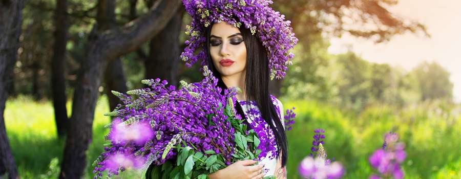 Pigemodel i skov med buket af lilla blomster og krans på hovedet lavet af lilla blomster