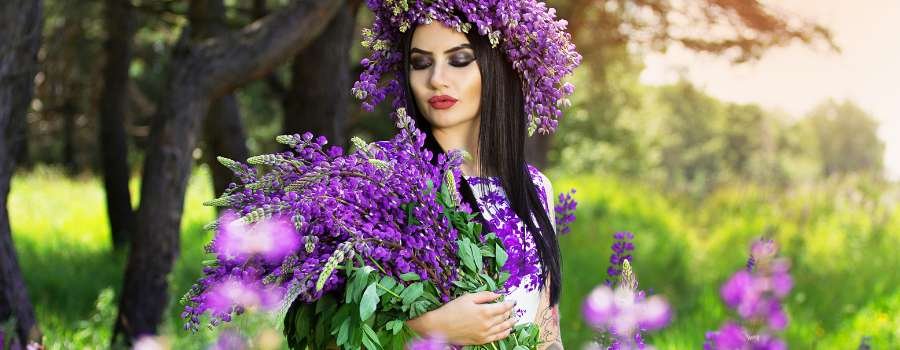 Pigemodel i skov med buket af lilla blomster og krans på hovedet lavet af lilla blomster