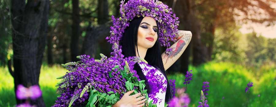 Pigemodel i skov med buket af lilla blomster og krans på hovedet lavet af lilla blomster