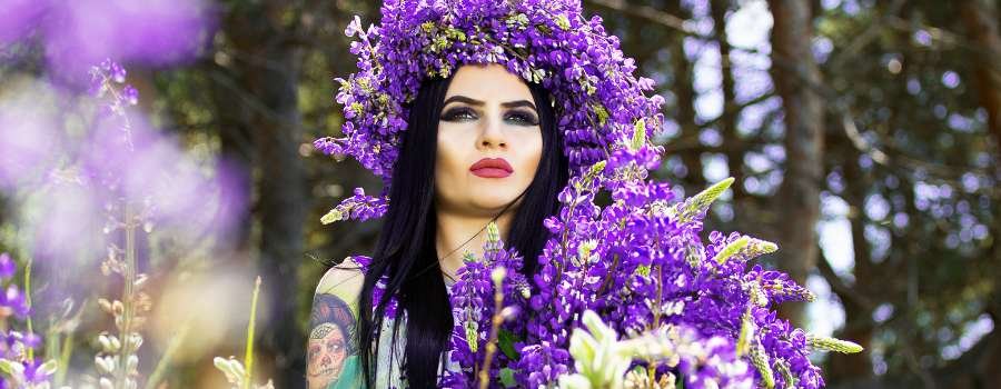 Pigemodel i skov med buket af lilla blomster og krans på hovedet lavet af lilla blomster