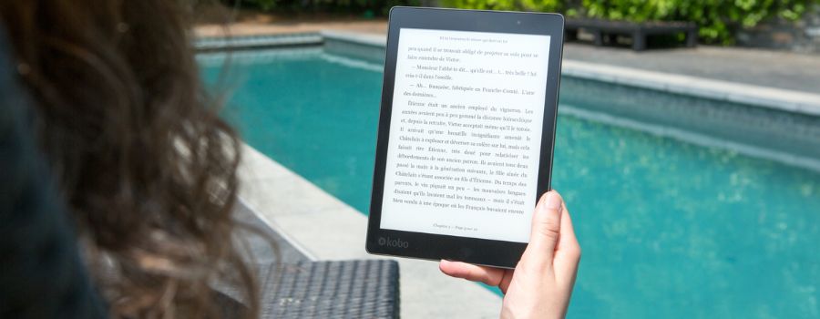 En pige med en e-bog i hænderne ved poolen