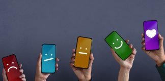 Fem hænder rakte op med smartphones, hvis skærme viser forskellige smileys på forskellige farvede baggrunde