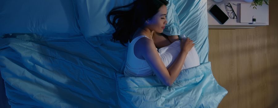 En asiatisk pige sover i sengen på hendes venstre side