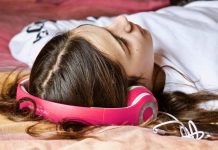 En pige med høretelefoner ligger på gulvet.