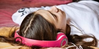 En pige med høretelefoner ligger på gulvet.