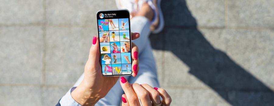 En kvindes hænder holder en telefon med et fotoalbum på skærmen.