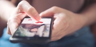 En pige holder en smartphone med en dating-app åben.