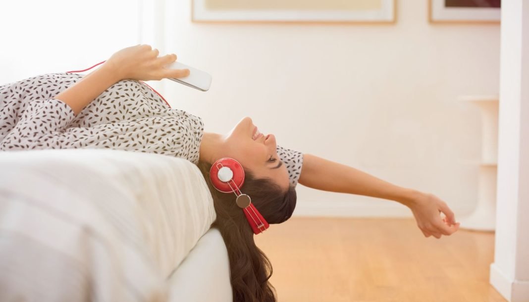 girl-in-headphones En pige med høretelefoner ligger på sengen.