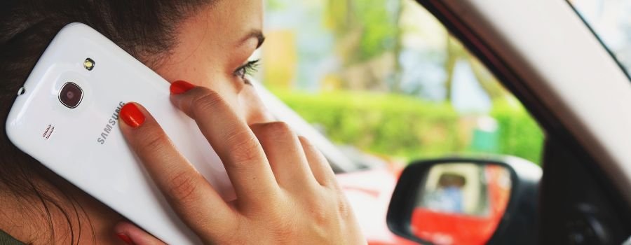 Pigen bag rattet taler i sin telefon, en hvid Samsung