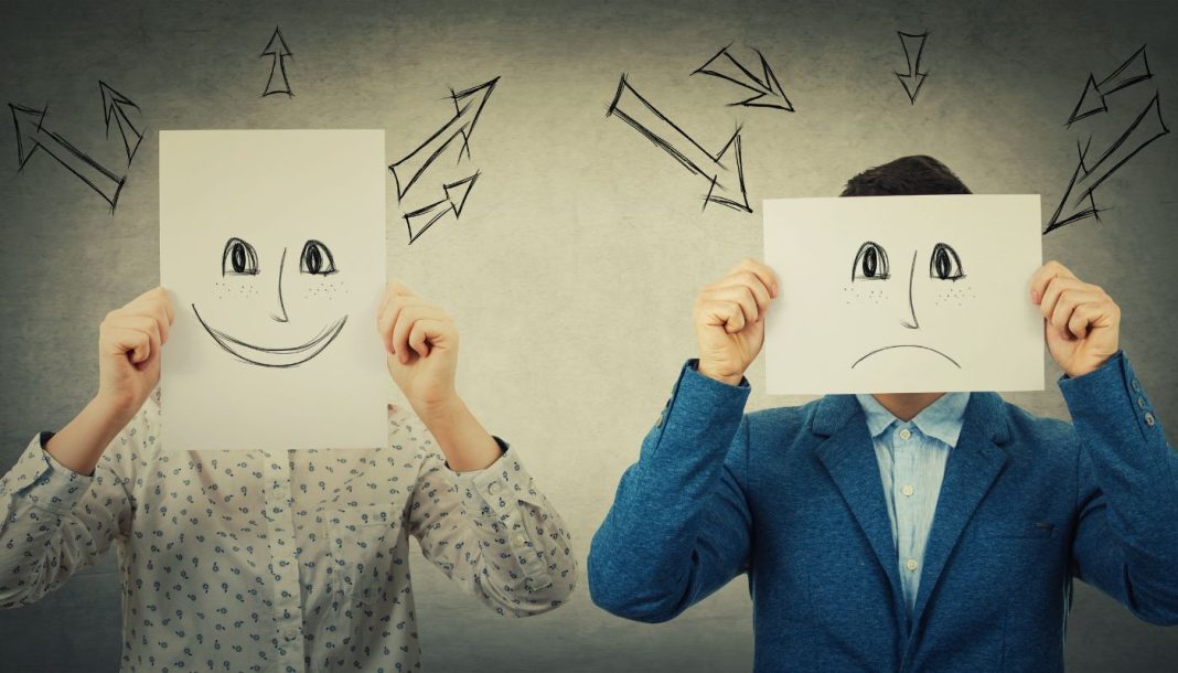 vs To fyre holder smileys tegnet på et stykke hvidt papir foran deres ansigter. Den venstre har en glad smiley, den højre en trist