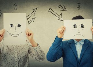 To fyre holder smileys tegnet på et stykke hvidt papir foran deres ansigter. Den venstre har en glad smiley, den højre en trist