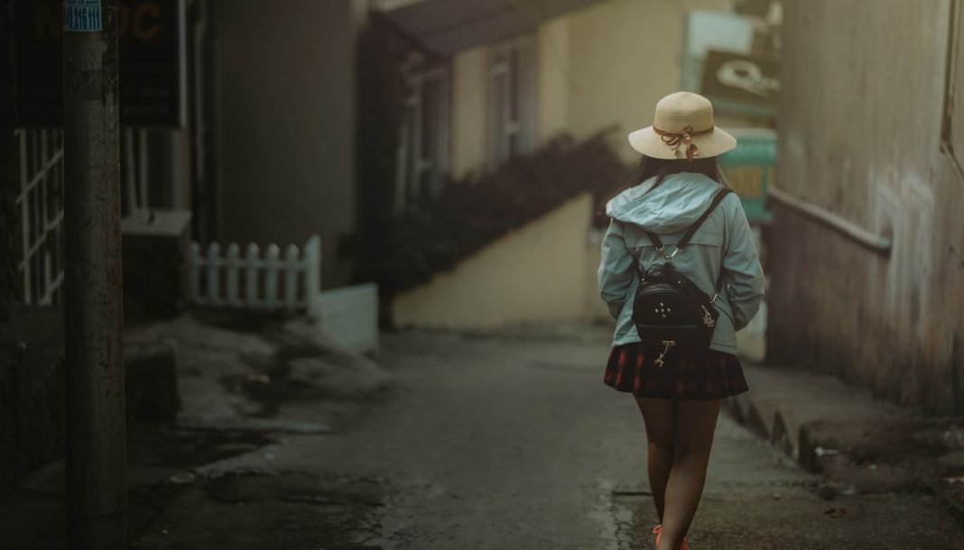 En pige med en sort rygsæk bag sig går ned ad en gade i byen.