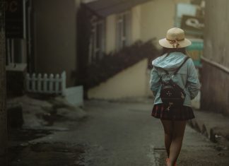 En pige med en sort rygsæk bag sig går ned ad en gade i byen.