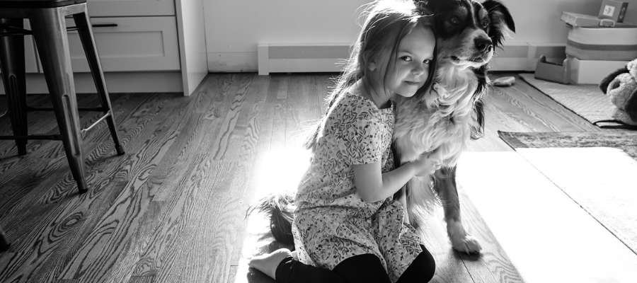 Pigen sidder på gulvet og krammer hunden.