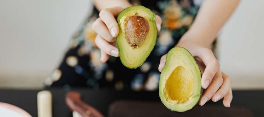 En kvinde holder to halvdele af en avocado