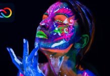 Kvinde med neonlys malet på ansigtet og hænderne på en sort baggrund, med Adobe Creative Cloud logo i øverste venstre hjørne.