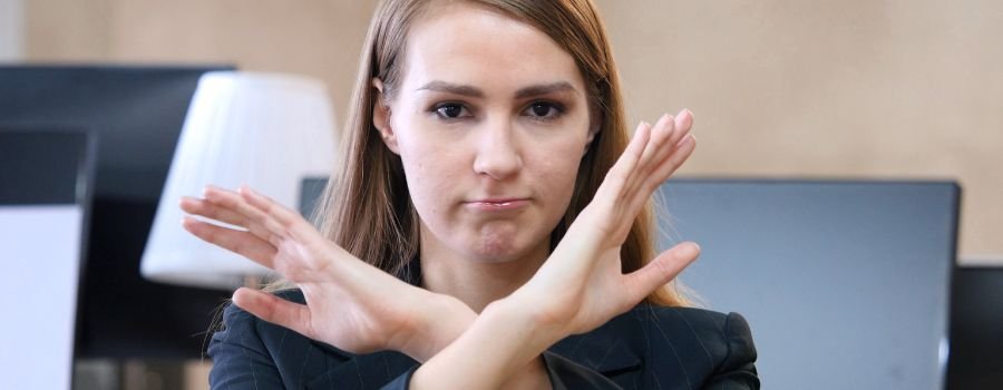 Kvinde viser stop- eller nej-gestus ved at krydse armene foran sig i form af et X.