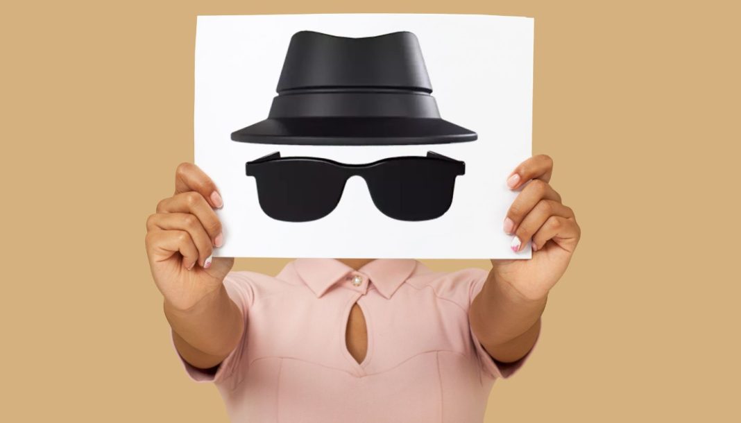 inkognitotilstand En person holder et ark med en tegning af en hat og solbriller, der symboliserer inkognito-tilstand