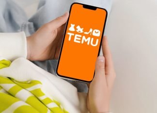 6 almindelige Temu-svindel og hvordan du undgår dem En persons hænder, der holder en smartphone med TEMU-logoet på en orange baggrund.