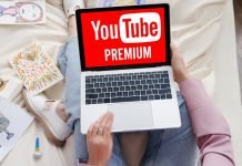 Kvinde med en bærbar computer på skødet, hvor YouTube Premium-logoet vises på skærmen.