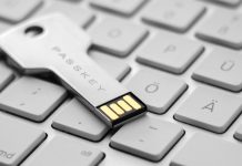 Et USB-drev i form af en nøgle med teksten "PASSKEY" indgraveret. Drevet ligger på et stilrent hvidt tastatur.