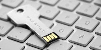 Et USB-drev i form af en nøgle med teksten "PASSKEY" indgraveret. Drevet ligger på et stilrent hvidt tastatur.