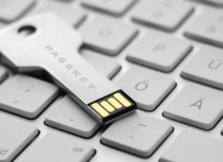 Et USB-drev i form af en nøgle med teksten "PASSKEY" indgraveret. Drevet ligger på et stilrent hvidt tastatur.