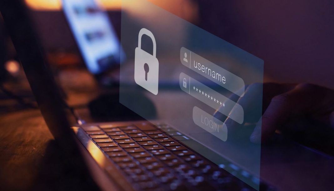 adgangskodeadministrator En nærbillede af en persons hænder, der taster et brugernavn og en adgangskode ind på en bærbar computer. Skærmen viser et login-vindue med et ikon af en lås.