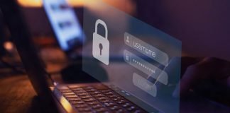 En nærbillede af en persons hænder, der taster et brugernavn og en adgangskode ind på en bærbar computer. Skærmen viser et login-vindue med et ikon af en lås.