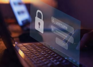 En nærbillede af en persons hænder, der taster et brugernavn og en adgangskode ind på en bærbar computer. Skærmen viser et login-vindue med et ikon af en lås.