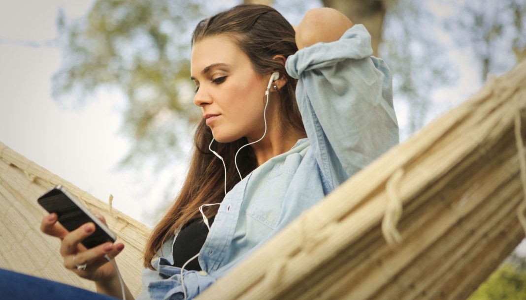 listening-music En pige sidder i en hængekøje og lytter til musik med øretelefoner.