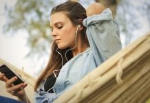 YouTube Music Playlister vs. Radiostationer: Hvad er forskellen? En pige sidder i en hængekøje og lytter til musik med øretelefoner.