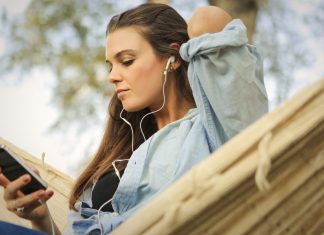 YouTube Music Playlister vs. Radiostationer: Hvad er forskellen? En pige sidder i en hængekøje og lytter til musik med øretelefoner.