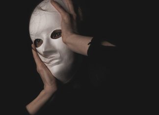 13 bedste deepfake apps: Lav realistiske og imponerende AI-videoer selv En person holder en hvid maske foran ansigtet i en mørk og mystisk atmosfære.