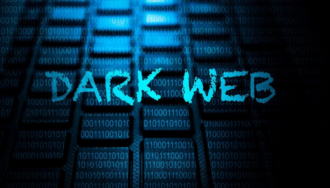 En baggrund af en computer-tastatur med binære tal (1 og 0) overlejret i blå farve. I forgrunden står teksten "DARK WEB" skrevet i en ru, blå skrifttype.