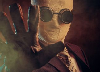 De 12 bedste dybe søgemaskiner til at udforske det usynlige web En person iført et jakkesæt, slips og specialiserede mørke briller, med ansigtet dækket af bandager, der rækker en handsket hånd frem mod kameraet. Baggrunden er mørk og tåget, hvilket skaber en mystisk og dramatisk atmosfære.