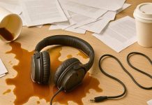 Sådan opbevarer du dine høretelefoner korrekt og undgår skader Hovedtelefonerne ligger i spildt kaffe på et skrivebord med dokumenter og to papkrus.